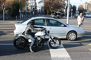 motorcycle pulled up next to a car at a red light